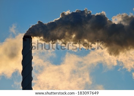 Factory pipe close-up with a lot of smoke against blue sky