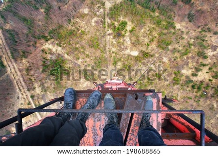 Urban explorers standing at the top of abandoned 200 meters tower in army boots
