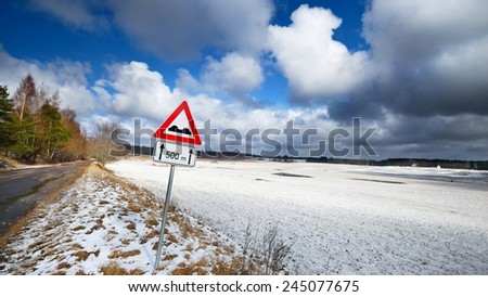 Old automobile road in countryside area and warning sign in winter.
