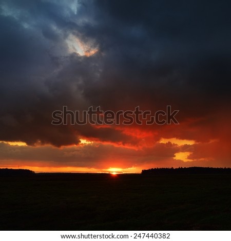 Sunset and the dramatic rain clouds over countryside landscape. Autumn in Latvia.