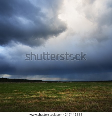 Dark dramatic rain clouds over countryside landscape. Autumn in Latvia.