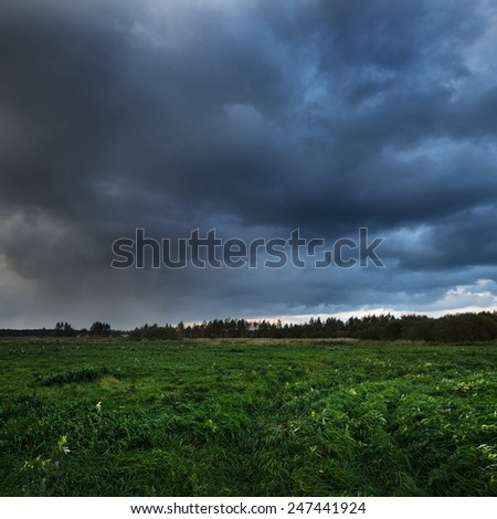 Dark dramatic rain clouds over countryside landscape. Autumn in Latvia.
