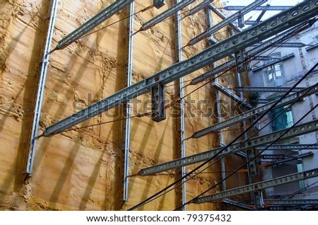 Steel beams supporting an old yellow wall and a building facade