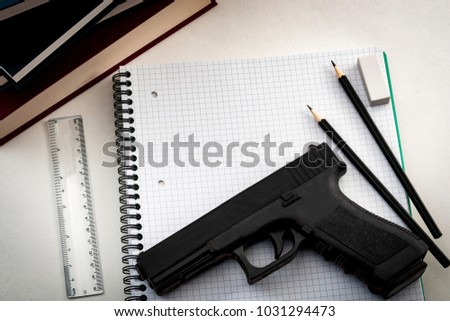 Gun control legislation and school shooting prevention concept with a gun on a notebook surrounded by school supplies and copy space