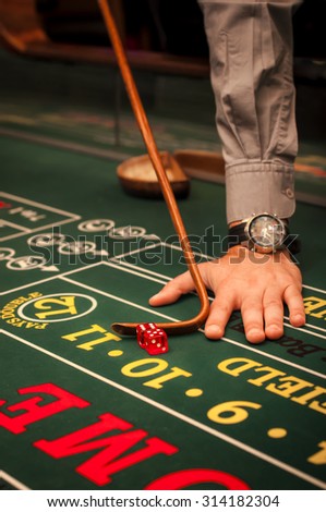 Casino dealer pushing a pair of dice on a craps table