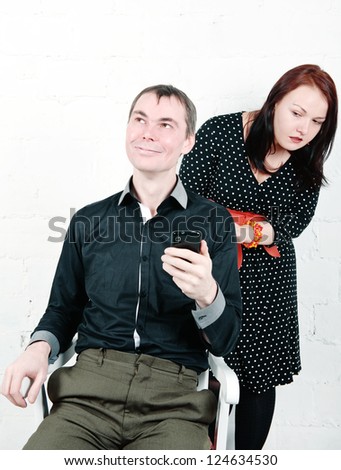 Jealous woman looking at her man chatting on telephone