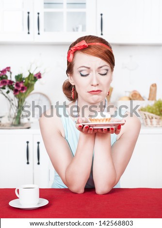 Sad beautiful young woman looking on cake