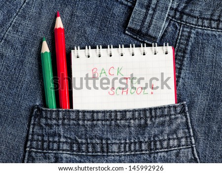 Notebook with phrase Back to school with red and green pencils in jeans pocket