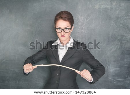 Angry teacher in glasses with wooden stick