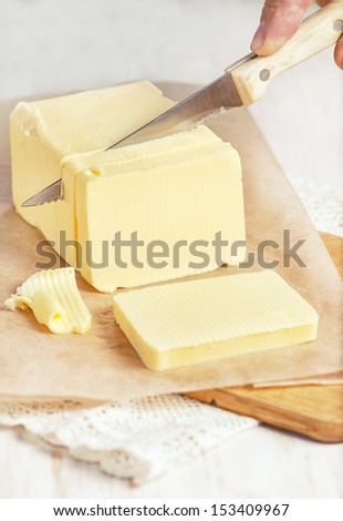 Piece of butter on paper cutting by knife