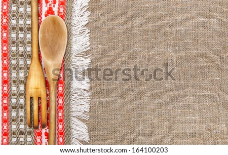 Burlap background bordered by country cloth and utensils