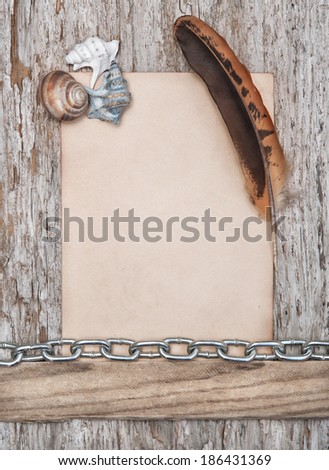 Paper, feather, seashells and metal chain on the old wood