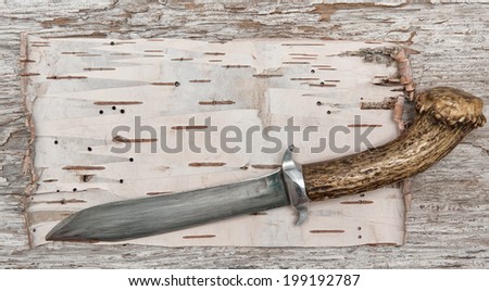 Old knife on the birch bark and wood