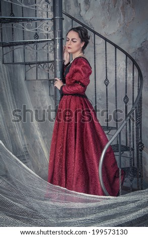 Sad beautiful  woman in medieval dress on the stairway