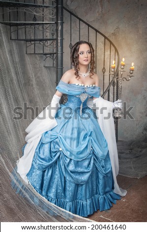 Beautiful woman in blue medieval dress with candelabrum