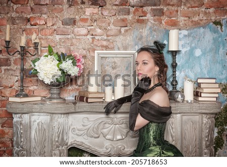 Beautiful woman in medieval dress near fireplace