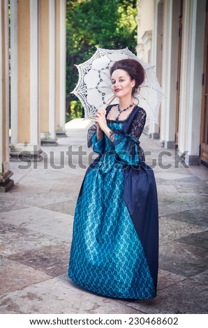 Beautiful young woman in blue medieval dress with umbrella