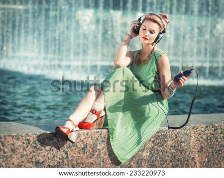 Hipster fashion girl in green dress listening music
