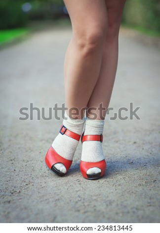 Red sandals with white socks on girl legs in fifties style