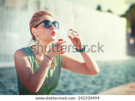 Beautiful young girl with pink hair in vintage clothing blowing bubbles outdoor