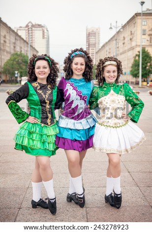 Three women in irish dance dresses and wig posing outdoor