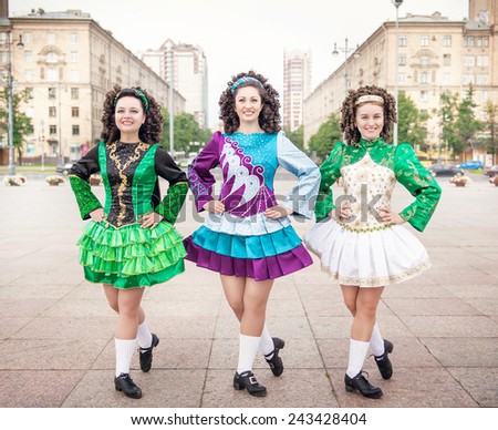 Three women in irish dance dresses and wig posing outdoor