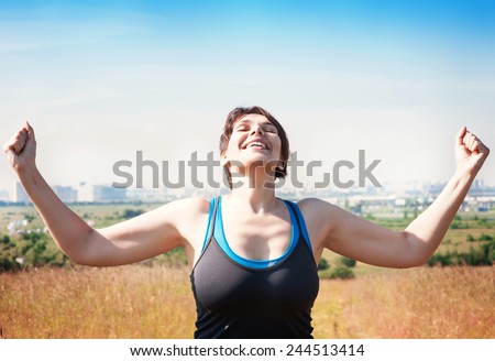 Happy beautiful successful plus size woman raising arms