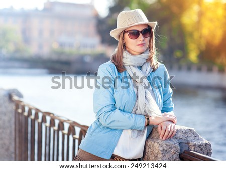 Beautiful young woman in hat, sunglasses and scarf outdoor in the city