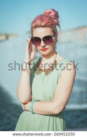 Beautiful young hipster woman with pink hair in vintage clothing in the city