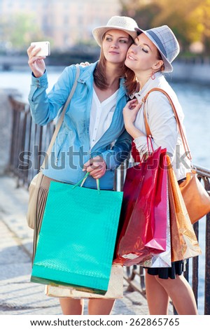 Two happy beautiful girls with shopping bags taken picture of themself in the city