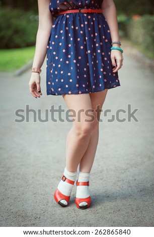 Red sandals with white socks on girl legs in fifties style outdoor