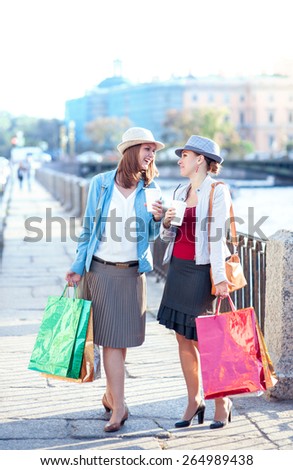 Two beautiful girls with shopping bags and cup of coffee in the city