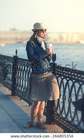 Beautiful young woman in hat and scarf enjoy sunlight outdoor in the city