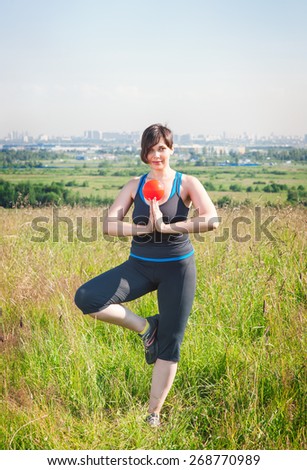 Beautiful plus size woman exercising with small ball outdoor