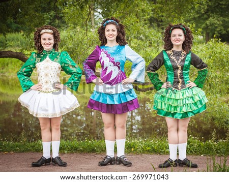 Three young beautiful girls in irish dance dress and wig posing outdoor