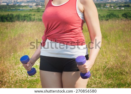 Plus size woman exercising with dumbbells outdoor