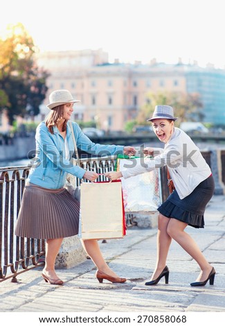 Two beautiful girls with shopping bags having fight in the city outdoor