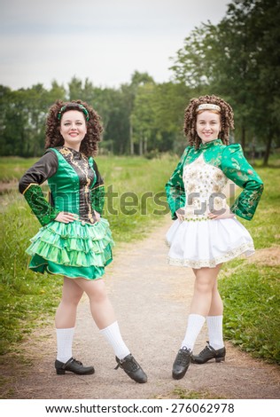 Two young beautiful girl in irish dance dress and wig posing outdoor
