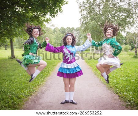 Three young beautiful girls in irish dance dress and wig posing outdoor