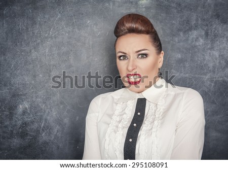 Scared teacher woman in white blouse on the blackboard background