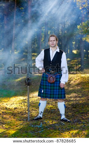 Brave man in scottish costume with sword in the forest