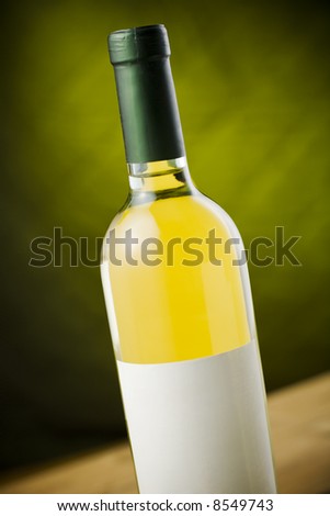 White wine bottle on wooden table over dark green / yellow background