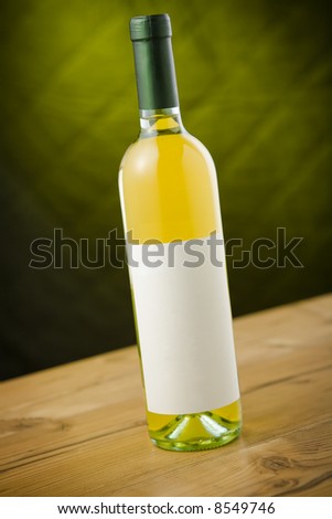 White wine bottle on wooden table over dark green / yellow background