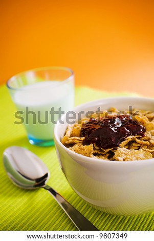 Corn flakes on the vase with jam and spoon