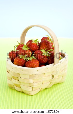 Basket filled with strawberries over lime table top.