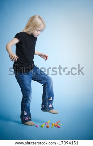 Young girl crushing plastic dinosaurus with her foot