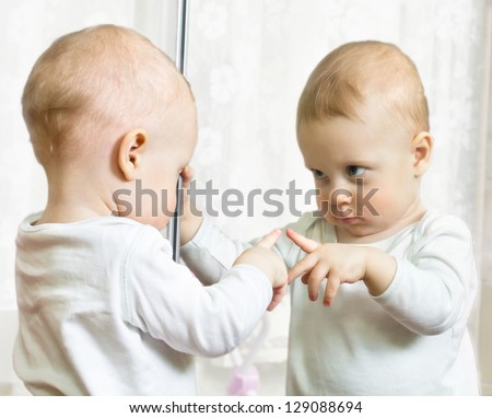 Ten month boy stands before the mirror