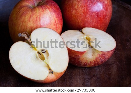 Three apples one cut open on dark background