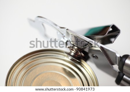 Tin opener opening a can of food isolated on white