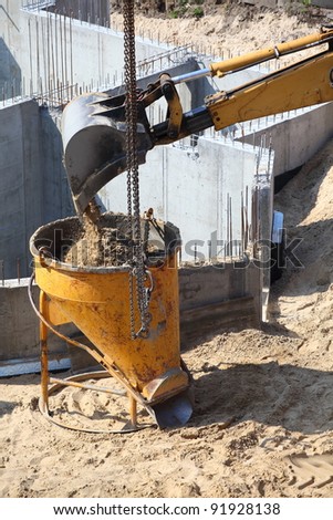 digger, excavator construction building site pouring concrete in form sand